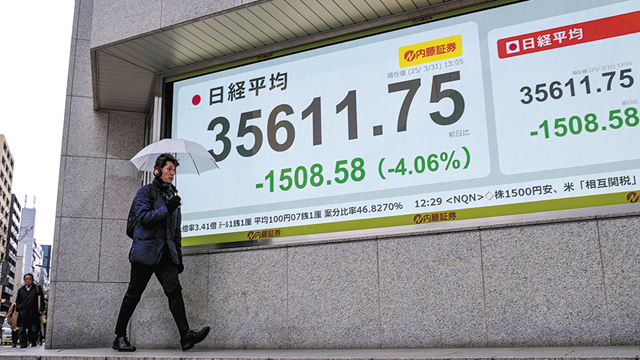 3月31日在日本东京，行人路过显示东京证券交易所行情的显示屏。新华社
